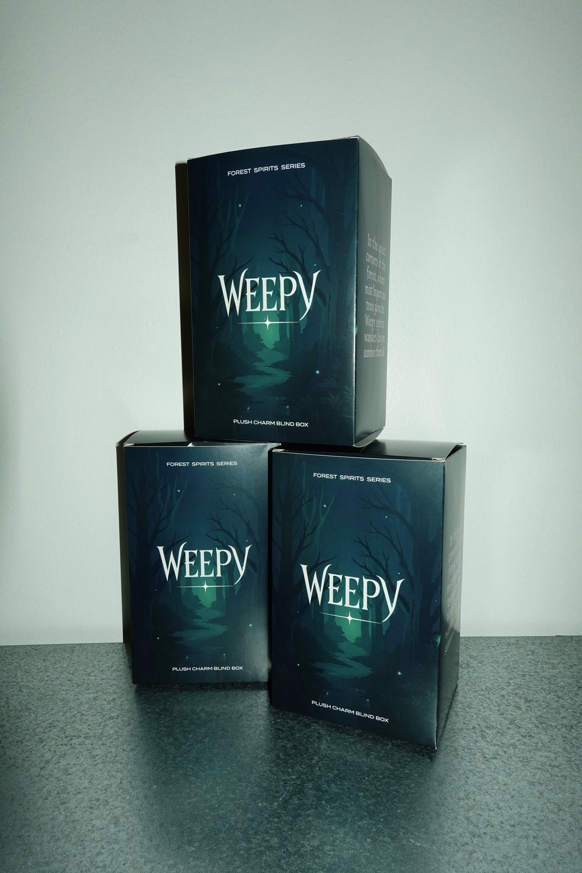 Three 'Weepy' plush charm blind boxes stacked on a gray surface with a white background